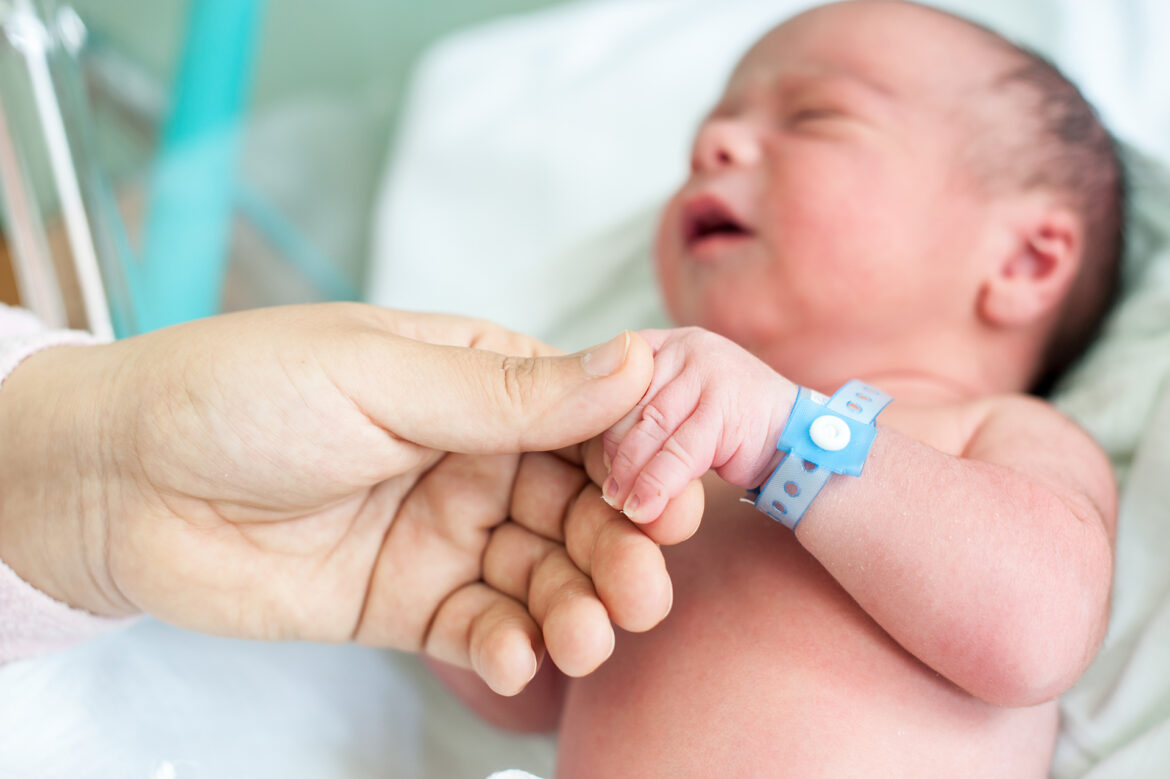 Newborn baby in hospital with id ribbon on his hand